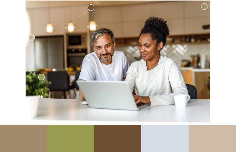 Eine Frau und ein Mann in legerer Kleidung sitzen zusammen an einem Laptop, im Hintergrund ist unscharf eine in warmen Farben gehaltene Küche zu sehen. Darunter eine Farbpalette mit den 5 wesentlichen Farben des Fotos: Dunkelbeige, Lindgrün, Braun, Taubengrau, Beige.